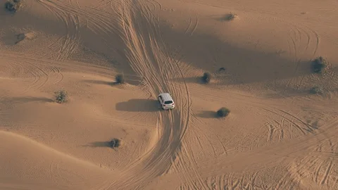 Aerial tracking shot of an unknown white SUV driving fast along sand dunes in Video stock 122743824