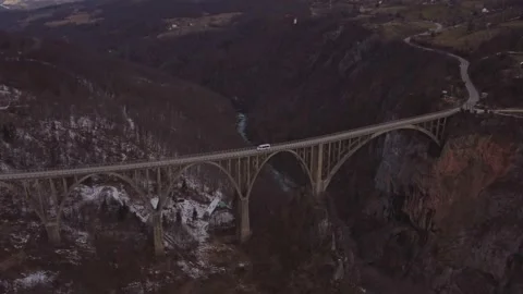 Aerial tracking shot of a white van driving across Durdevica Tara Bridge in Stock Footage 341069231