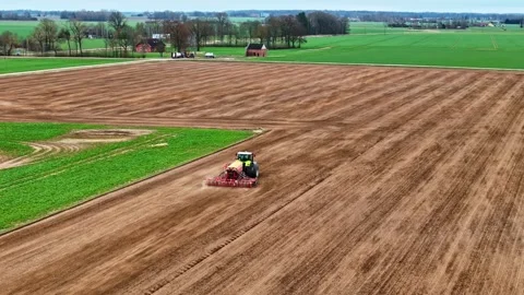 Aerial Tracking of Tractor with Seed Drill Sowing Spring Crop on Vast Plowed Stock Footage 333999989