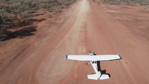Aerial tracking view of Cessna 172 taking off on dirt airstrip  Stock Footage 92556700
