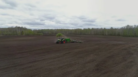 Aerial Tracking View of a Working Tractor in the Farm Field. Sowing the Soil Stock Footage 127980579