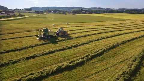 Aerial of tractor makes hay bales and drops them covered in plastic Stock Footage 73020005