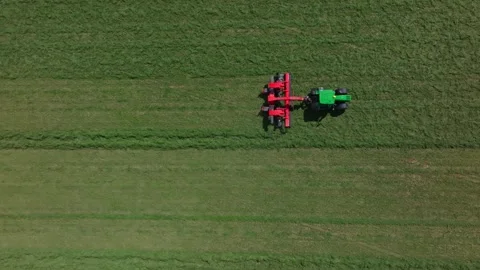 Aerial tractor with mower cuts parallel rows in rural hay field Stock Footage 324795300