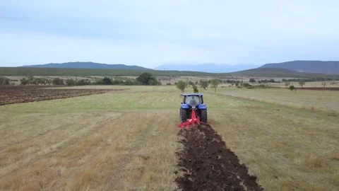 Aerial - Tractor plowing a field. A first step in cultivating the land Stock Footage 116077064