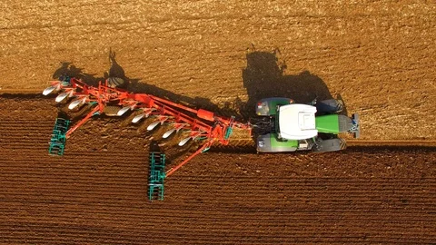 Aerial: Tractor plows a field in spring -Tractor cultivating a field in  spring Stock Footage 88493843