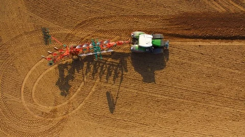 Aerial: Tractor plows a field in spring -Tractor cultivating a field in  spring Stock Footage 88499312