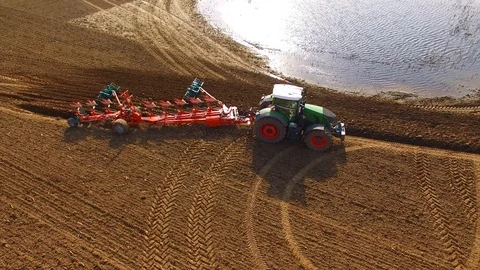 Aerial: Tractor plows a field in spring -Tractor cultivating a field in  spring Stock Footage 88499347