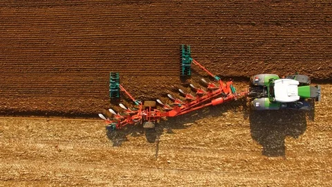 Aerial: Tractor plows a field in spring -Tractor cultivating a field in  spring Stock Footage 88499881