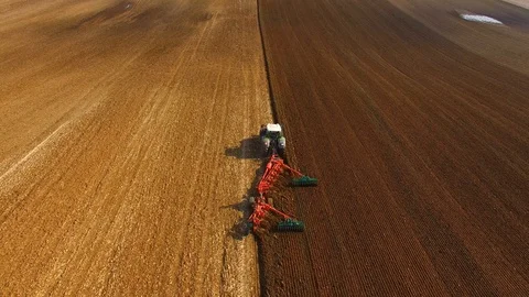 Aerial: Tractor plows a field in spring -Tractor cultivating a field in  spring Stock Footage 88502456