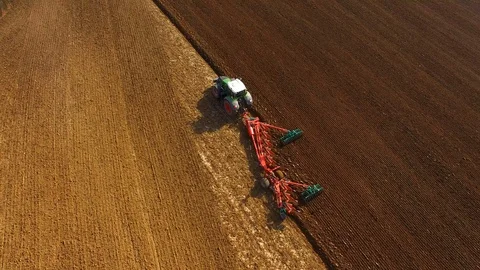 Aerial: Tractor plows a field in spring -Tractor cultivating a field in  spring Stock Footage 88502864