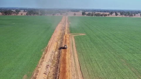 Aerial of a tractor pulling a small road grader along a dirt farm road Stock Footage 276971465