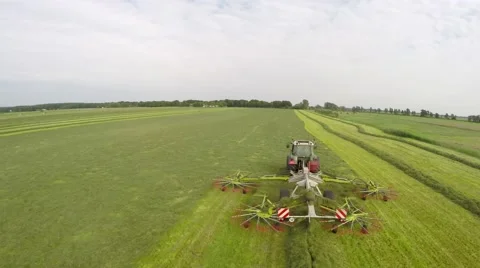 Aerial of tractor working low fly over the vehicle mowing grass turning grass 4k Stock Footage 52131219