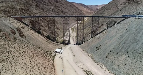 Aerial of train driving through old bridge at desertic mountainous landscape 스톡 동영상 107215470