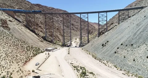 Aerial of train driving through old metal bridge at desertic mountainous valley 스톡 동영상 126603985