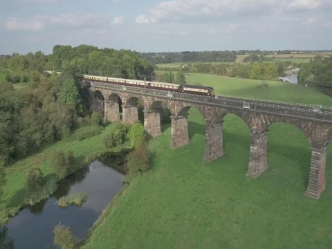 Aerial of Train Going Over Bridge In British Countryside Stock Footage 77765071