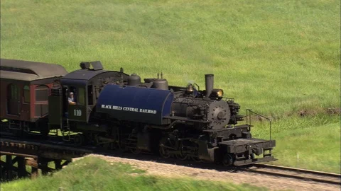 Aerial of train running on tracks through grass field, Following black steam Stock Footage 109449838