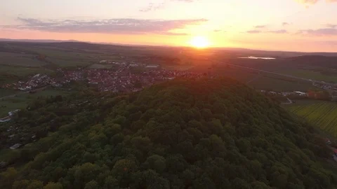 Aerial of tree covered mountain and village at sunset Stock Footage 116203988