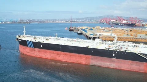 Aerial of tugboat pulling cargo ship away in the harbor Video stock 116487885