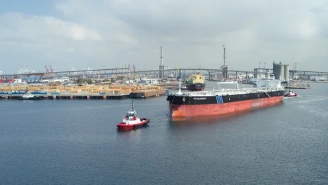 Aerial of tugboat pulling cargo ship away in the harbor Video stock 116488199