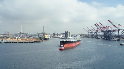 Aerial of tugboat pulling cargo ship away in the harbor Stock Footage 116488333