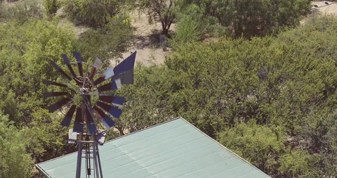 AERIAL TURNAROUND OF A SMALL WINDMILL IN THE MIDDLE OF A LAKE WATER 4K Stock Footage 101243604