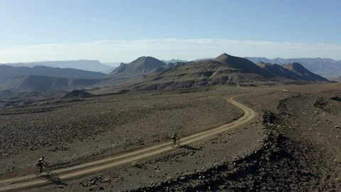 An aerial of two cyclists descending through an endless desert landscape. Stock Footage 127018245