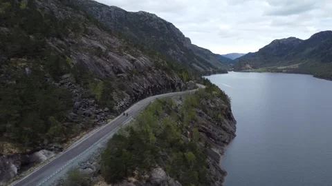 Aerial of two cyclists riding on a mountain road next to a fjord in Norway Video stock 335198474