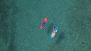Aerial: Two Girlfriends Stand Up Paddle Boarding In Stunning Crystal Clear Ocean Stock Footage
