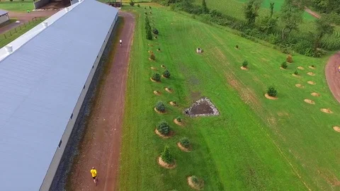 Aerial Two Men Running Alongside Large Warehouse Country Farm Building Stock Footage 71325487