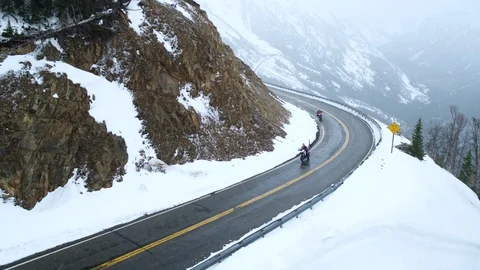 Aerial of two motorcyclists going down mountain road in winter, Wyoming, USA Stock Footage 124215702