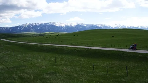 Aerial of two motorcyclists riding through green pastures, Wyoming USA Stock Footage 124217645