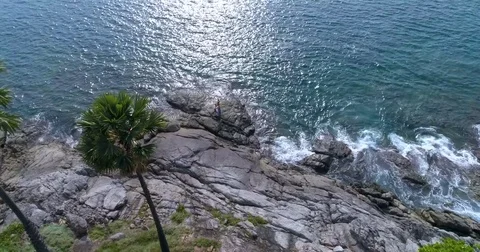 Aerial: Two partners doing Acro Yoga on the rocks near the sea. Video stock 82189375