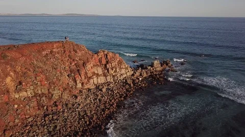 Aerial of two people on remote desert coast with view of vast ocean at sunset Stock Footage 123949987