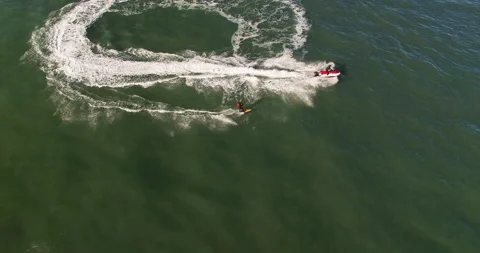 Aerial of two pro surfers using surfing board and jet ski to travel across ocean Stock Footage 155795664