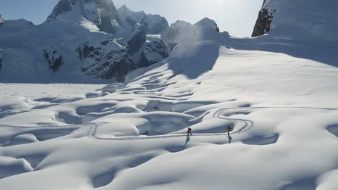 Aerial of two Ski Mountaineers going down mountain surface covered in snow Stock Footage 121593473