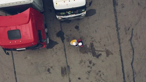 AERIAL. Two workers works on tablet near trucks. Camera zooming out. Stock Footage 111404431