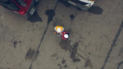 AERIAL. Two workers works on tablet near trucks. Camera zooming out. Stock Footage 111404554