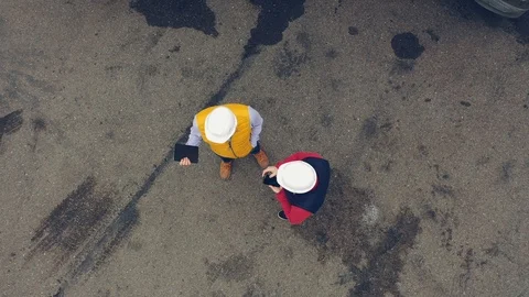 AERIAL. Two workers works on tablet near trucks. Camera zooming out. Stock Footage 111404943