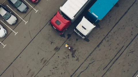 AERIAL. Two workers works on tablet near trucks. Camera zooming out. Stock Footage 111405047