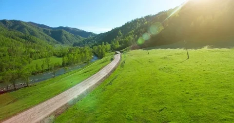 Aerial UHD 4K view. Low air flight over mountain rural dirt road and meadow Stock Footage