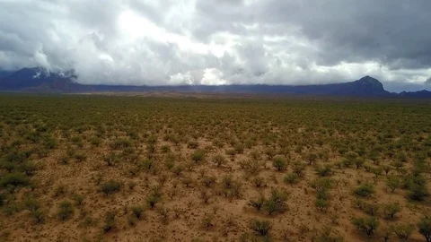 Aerial of a vast high desert with cloud covered mountains in the distance Stock Footage 83520740