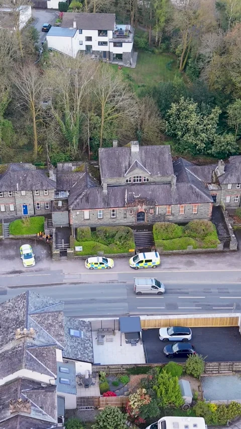 Aerial vertical descent over Windermere Police Station as police car parks Vídeos de archivo 334132201