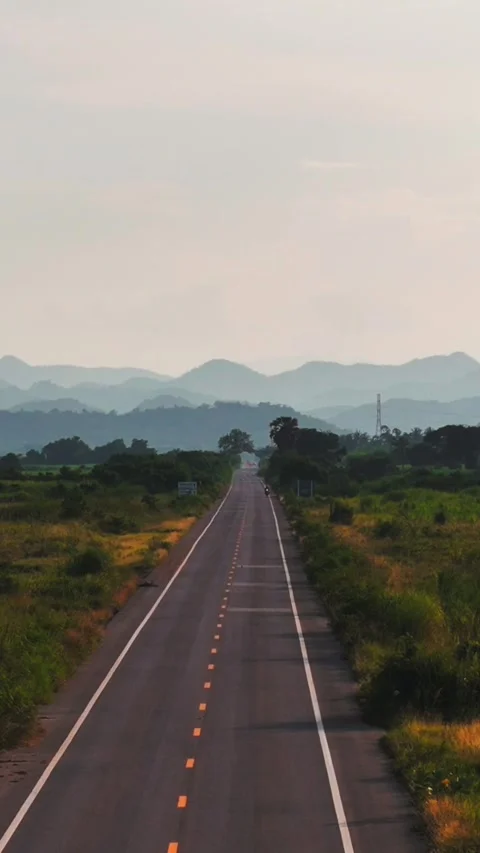 Aerial Vertical Dolly Zoom Effect Over Long Straight Road Across Green Valley Stock Footage 318722016
