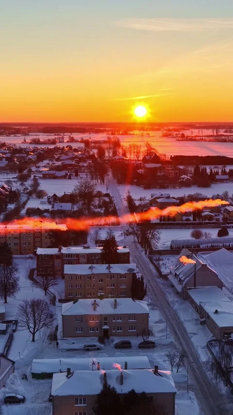 Aerial vertical pull back from snowy houses to industrial plant at sunset in Stock Footage 336239176