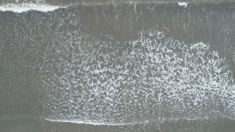 Aerial vertical view at large waves crashing against a beach on cloudy day Stock-Footage 97235882