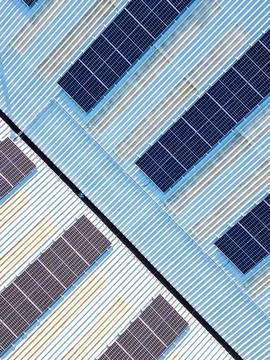 Aerial vertical view of solar panel photovoltaic cells on roof of factory, UK Stock Photos