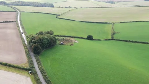 Aerial video clip of a tractor at the margin of a large field with a van driving Stock Footage 167181302