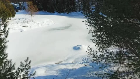 Aerial video of a drone passing between trees in winter moving toward the sti Stock Footage 164420625