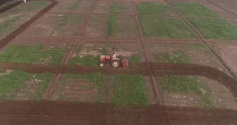 Aerial video made while flying above a farm and a tractor on the ground Stock Footage 291677839