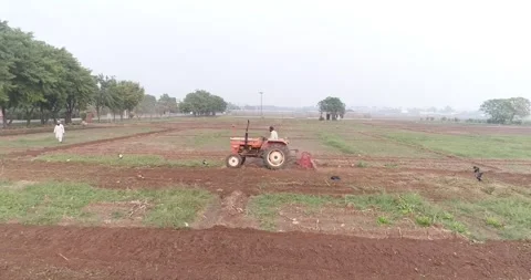 Aerial video made while flying above a farm and a tractor on the ground Stock Footage 291677857